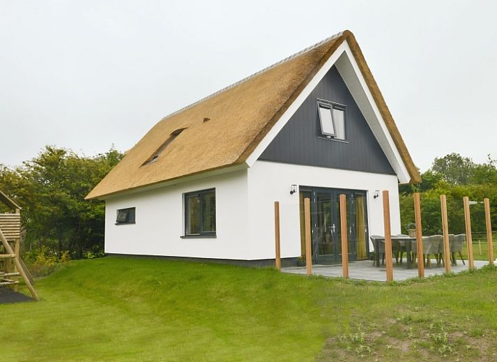 De Postschipper vakantiehuis met rieten dak in De Cocksdorp, Texel, omringd door groen.