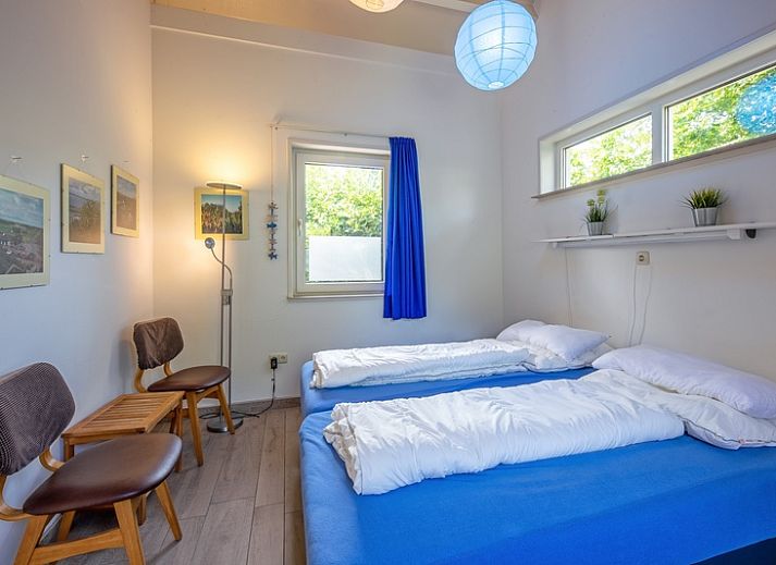 Cozy living room in Holiday home Slufterhoek 174, De Cocksdorp Texel with comfortable chairs and fireplace.