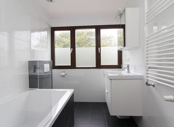 Vakantiehuis D 491 in De Cocksdorp, Texel, biedt een prachtig uitzicht op een groene tuin en blauwe lucht, ideaal voor een ontspannen verblijf.