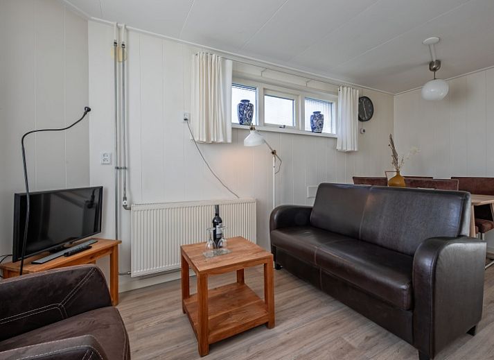 Rustikales Ferienhaus Kikkertstraat 60 in De Cocksdorp, Texel mit Holzfassade und gruener Umgebung.