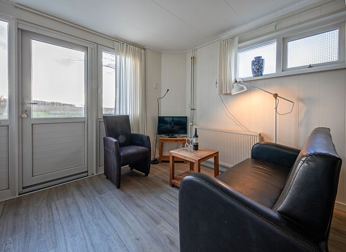 Rustikales Ferienhaus Kikkertstraat 60 in De Cocksdorp, Texel mit Holzfassade und gruener Umgebung.