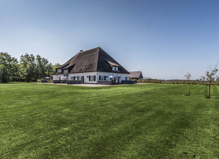 Gezellige woonkamer in Type R vakantiehuis, De Cocksdorp, Texel, met grote ramen en comfortabele zitplaatsen.