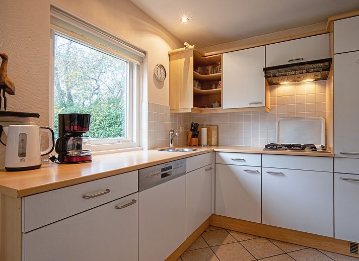 Cozy living room of Holiday home Slufterduin 094 in De Cocksdorp, Texel, with comfortable seating area and views of the green garden.