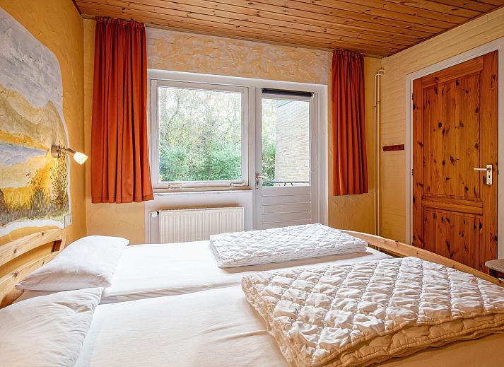 Cozy living room of Holiday home Slufterduin 094 in De Cocksdorp, Texel, with comfortable seating area and views of the green garden.