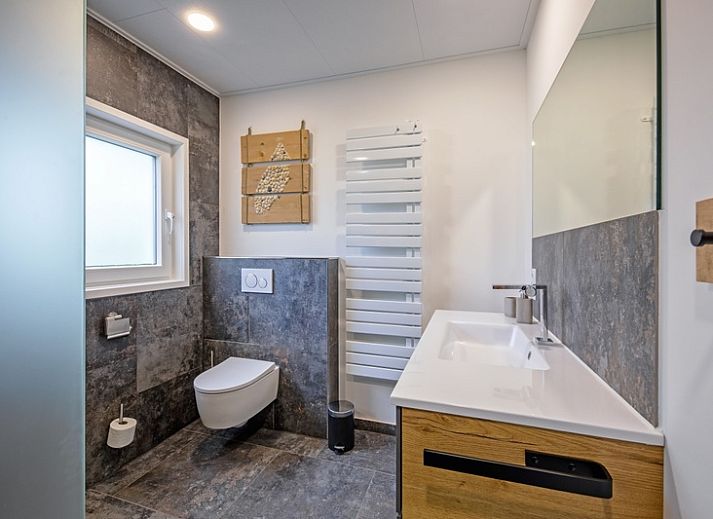 Lichte woonkamer van Vakantiehuis Slufterhoek 158 in De Cocksdorp, Texel, met moderne inrichting en uitzicht op de tuin.