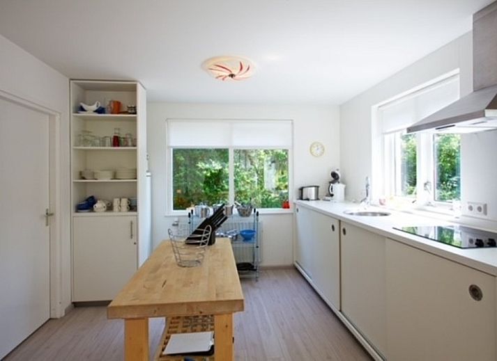 Gezellig terras bij Bungalow Schelpenoord - Vakantiehuis De Oester in De Cocksdorp, Texel, met parasol en tuinmeubilair.