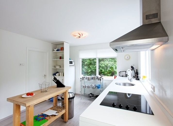 Gezellig terras bij Bungalow Schelpenoord - Vakantiehuis De Oester in De Cocksdorp, Texel, met parasol en tuinmeubilair.