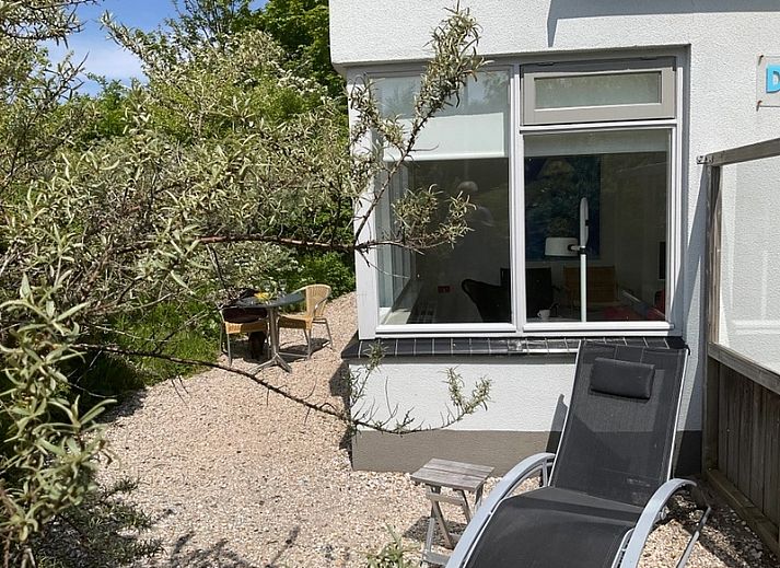 Lichte woonkamer in Bungalow Schelpenoord - Vakantiehuis De Oester, De Cocksdorp, Texel, met kleurrijke stoelen en moderne inrichting.