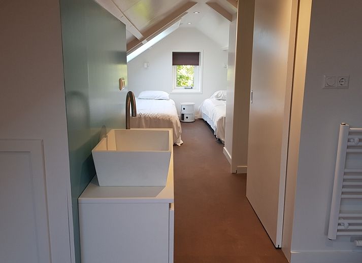 Lichte woonkamer in Bungalow Schelpenoord - Vakantiehuis De Oester, De Cocksdorp, Texel, met kleurrijke stoelen en moderne inrichting.