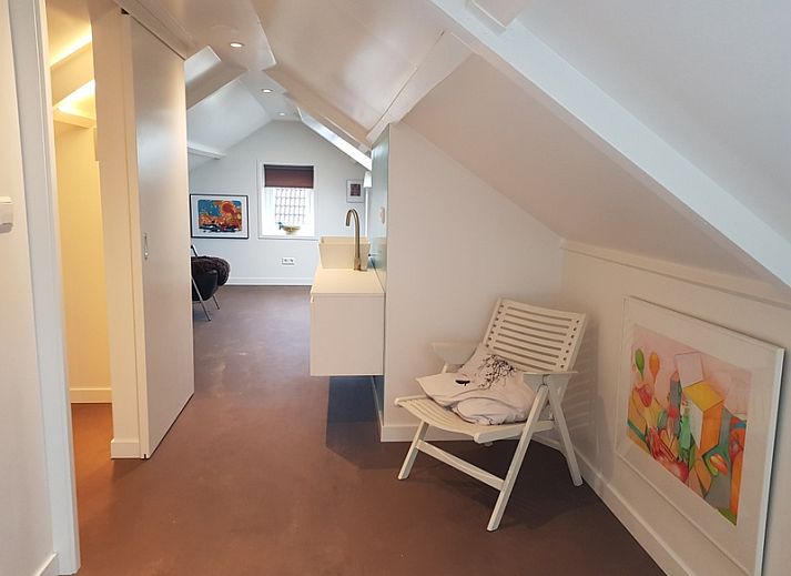 Lichte woonkamer in Bungalow Schelpenoord - Vakantiehuis De Oester, De Cocksdorp, Texel, met kleurrijke stoelen en moderne inrichting.