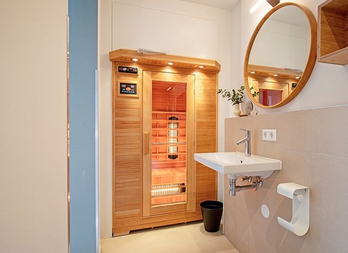 Cozy living room with large window in Holiday home De Razende Bol, De Cocksdorp, Texel, overlooking the garden.