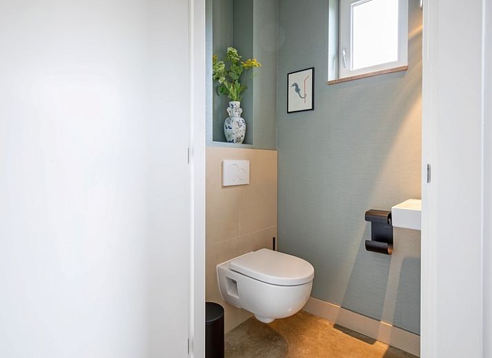 Cozy living room with large window in Holiday home De Razende Bol, De Cocksdorp, Texel, overlooking the garden.