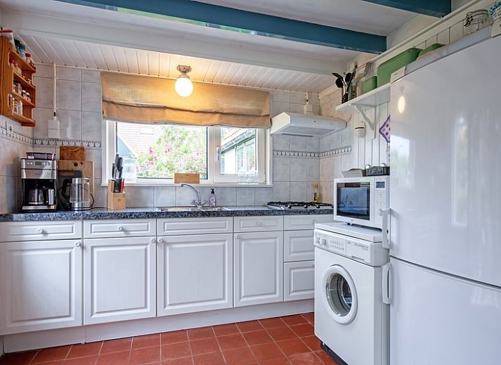 Charmant vakantiehuis Muyweg 062 in De Cocksdorp, Texel met een rustieke tuin en rode dakpannen.