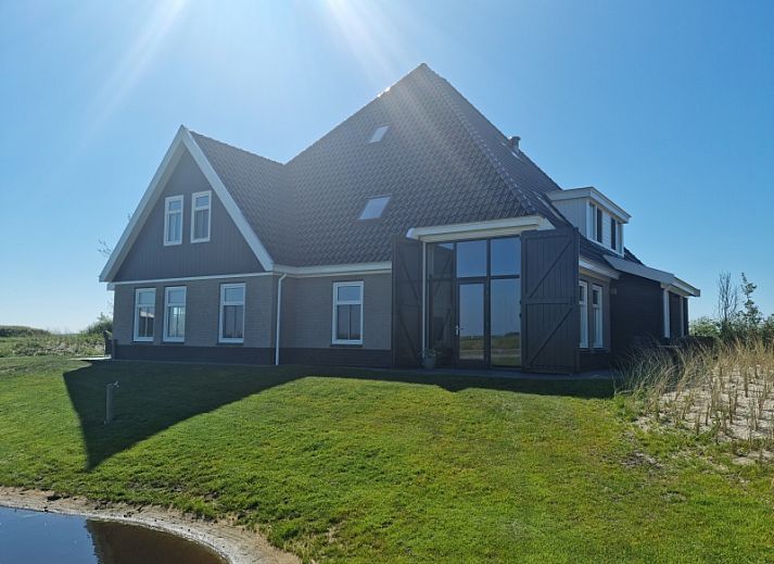 Vakantiehuis Eierland in De Cocksdorp, Texel biedt een prachtig uitzicht op de natuur met een vijver en groene omgeving.