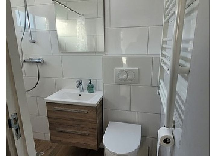Lichte woonkamer van Bungalow Tamarisk 190 in De Cocksdorp Texel met comfortabele zithoek en uitzicht op de tuin.