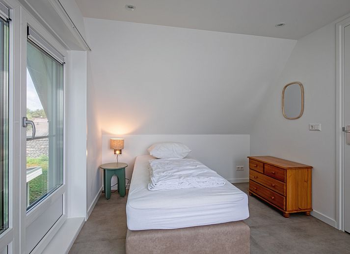 Lichte woonkamer van Vakantiehuis Slufterhoek 104 in De Cocksdorp, Texel met moderne meubels en grote ramen.