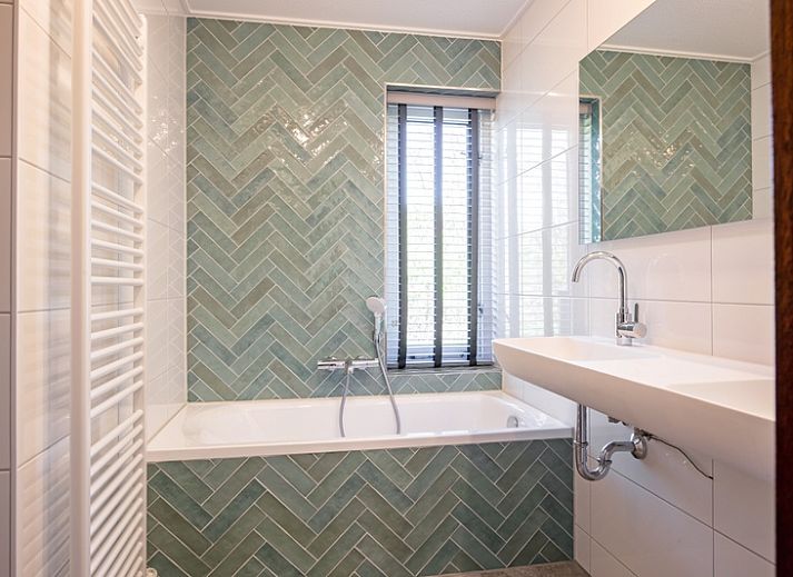 Gemuetliches Wohnzimmer des Ferienhauses Schelpenoord 135 in De Cocksdorp, Texel mit bequemen Sofas und viel Tageslicht.