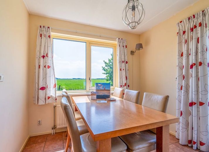 Lichte woonkamer in Vakantiehuisje in De Cocksdorp, Texel met comfortabele zithoek en uitzicht op de tuin, ideaal voor ontspanning.