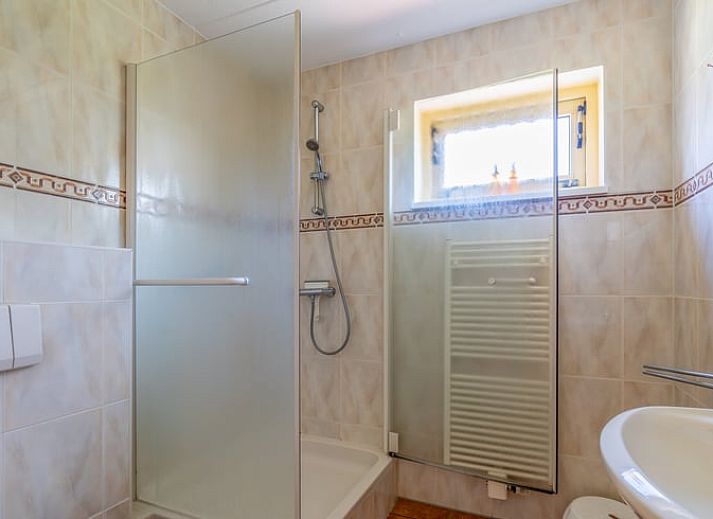 Lichte woonkamer in Vakantiehuisje in De Cocksdorp, Texel met comfortabele zithoek en uitzicht op de tuin, ideaal voor ontspanning.