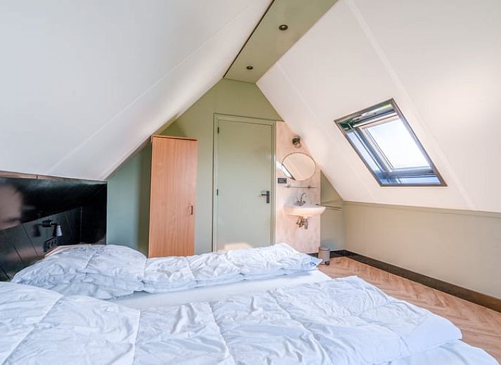 Lichte woonkamer in Vakantiehuisje in De Cocksdorp, Texel met comfortabele zithoek en uitzicht op de tuin, ideaal voor ontspanning.
