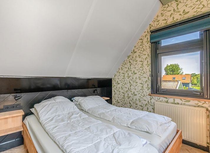 Lichte woonkamer van Vakantiehuisje in De Cocksdorp, Texel met uitzicht op groene natuur en ruime eethoek, ideaal voor ontspanning.