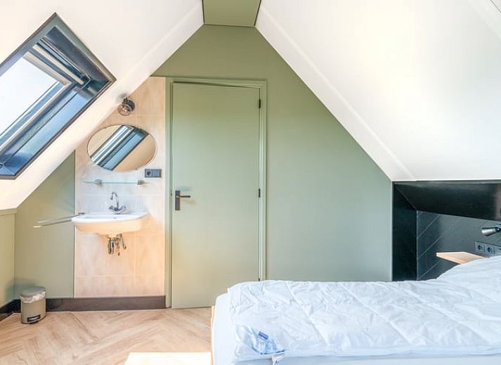 Lichte woonkamer van Vakantiehuisje in De Cocksdorp, Texel met uitzicht op groene natuur en ruime eethoek, ideaal voor ontspanning.