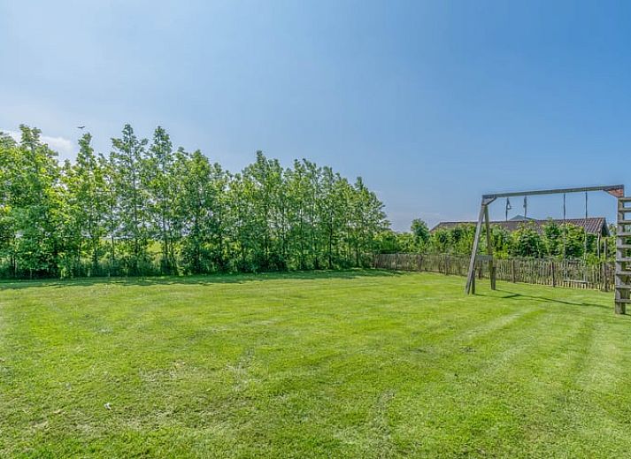Lichte woonkamer van Vakantiehuisje in De Cocksdorp, Texel met uitzicht op groene natuur en ruime eethoek, ideaal voor ontspanning.