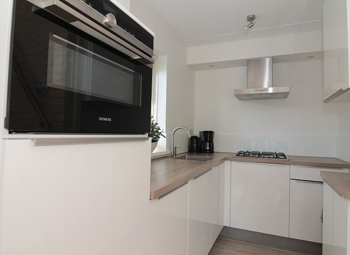 Ingang van Vakantiehuis B 289 in De Cocksdorp, Texel, omgeven door een groene tuin en rustieke stenen muren.