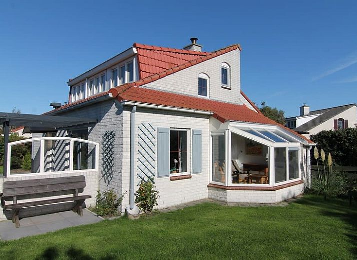 Vooraanzicht van Vakantiehuis D 493 in De Cocksdorp, Texel, met een ruime oprit en groene haag, ideaal voor een ontspannen verblijf op de Waddeneilanden.