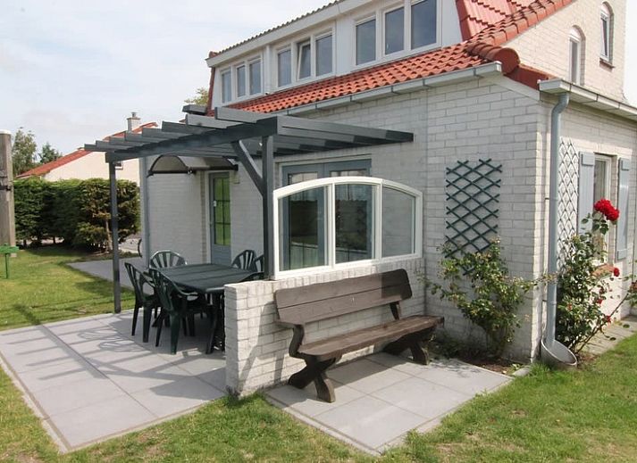 Vooraanzicht van Vakantiehuis D 493 in De Cocksdorp, Texel, met een ruime oprit en groene haag, ideaal voor een ontspannen verblijf op de Waddeneilanden.