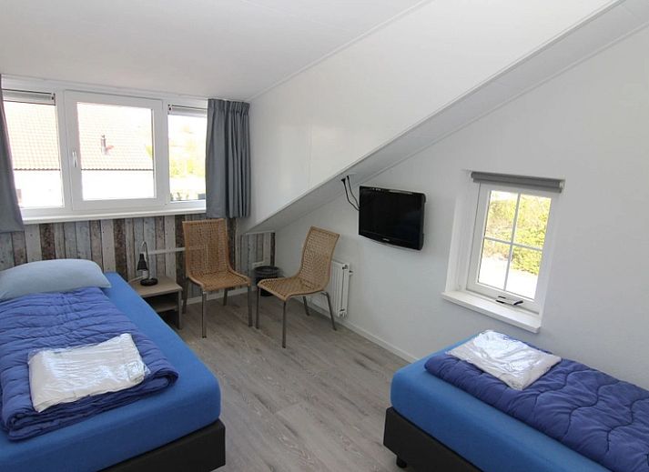 Spacious garden at Holiday home D 669 in De Cocksdorp, Texel with green surroundings and terrace with parasol, ideal for relaxation on the Wadden Islands.