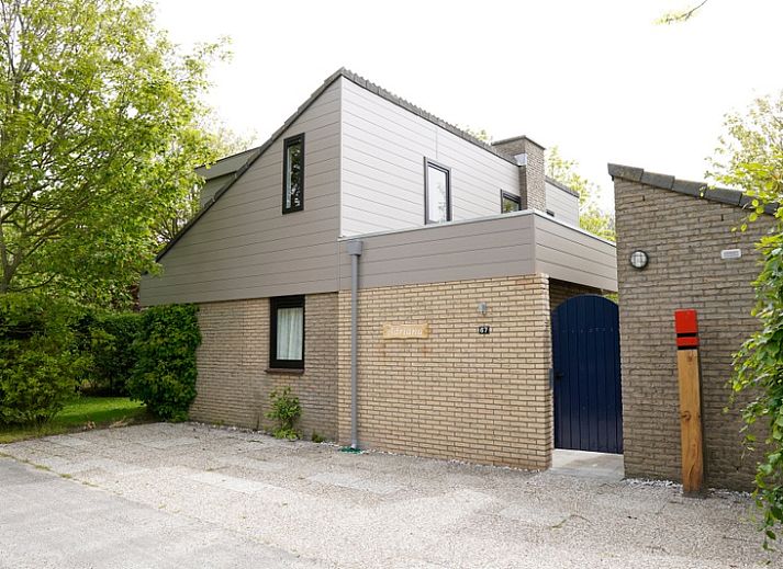 Vakantiehuis C 067 in De Cocksdorp, Texel biedt een charmante buitenkant omgeven door groen, ideaal voor een ontspannen verblijf op de Waddeneilanden.