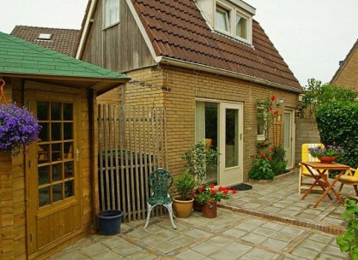 Gemuetliche Terrasse am Ferienhaus Dunaa in De Koog, Texel, umgeben von Blumen und Sitzgelegenheiten.