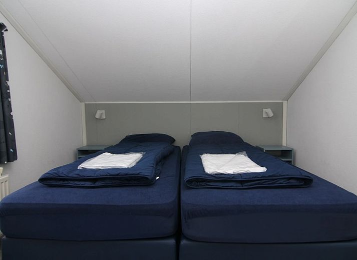 Das Ferienhaus D 618 in De Cocksdorp, Texel, bietet einen schoenen Aussenbereich mit gruenen Hecken und einer einladenden Terrasse.