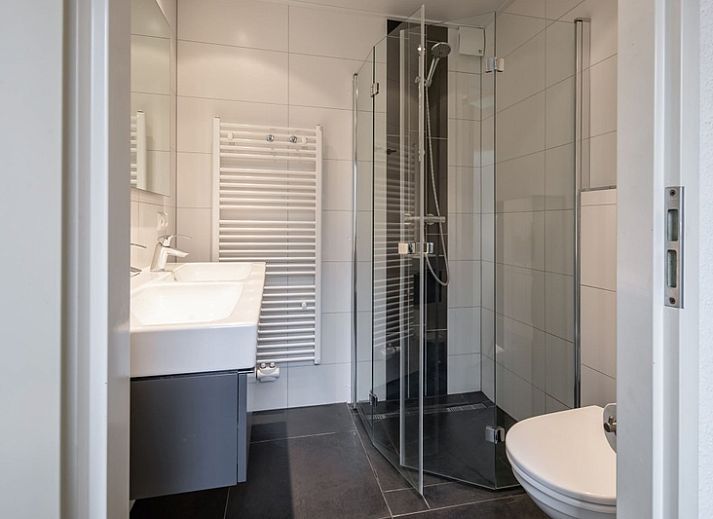 Vakantiehuis B 387 in De Cocksdorp, Texel omgeven door groen met zonnig terras en comfortabele stoelen, ideaal voor ontspanning op de Waddeneilanden.