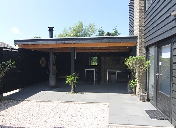 Vakantiehuis C 081 in De Cocksdorp, Texel, biedt een charmant terras met uitzicht op een weelderige tuin en moderne architectuur.