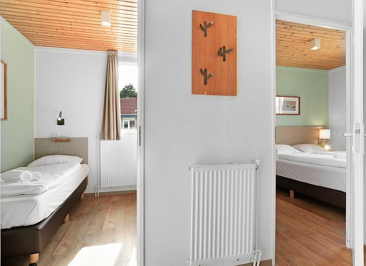 Gezellige woonkamer in Sluftervallei 6-persoons bungalow 6C, Texel, met grote ramen en comfortabele zithoek.