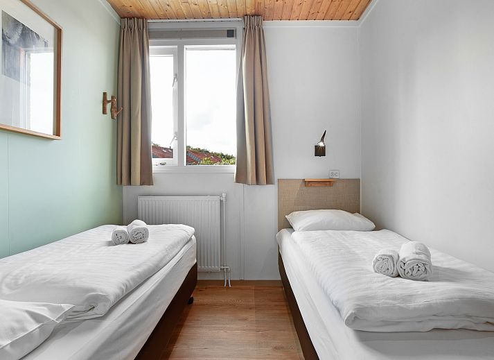 Gezellige woonkamer in Sluftervallei 6-persoons bungalow 6C, Texel, met grote ramen en comfortabele zithoek.