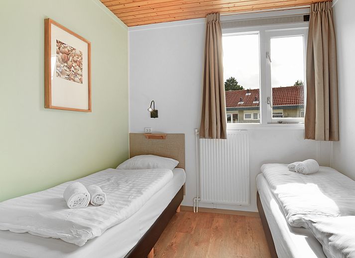 Gezellige woonkamer in Sluftervallei 6-persoons bungalow 6C, Texel, met grote ramen en comfortabele zithoek.