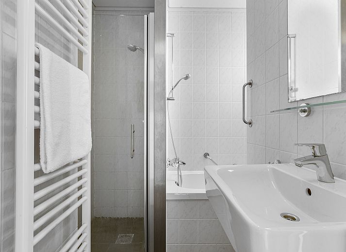 Gezellige woonkamer in Sluftervallei 6-persoons bungalow 6C, Texel, met grote ramen en comfortabele zithoek.