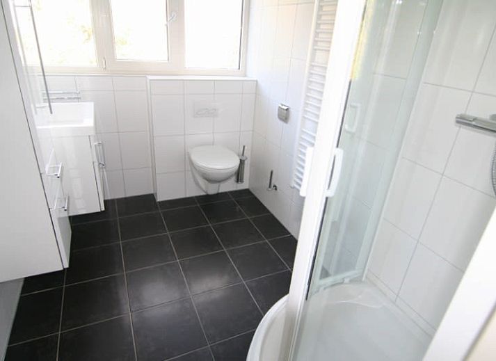 Das Ferienhaus D 760 in De Cocksdorp, Texel, bietet eine ruhige Gartenumgebung mit gruenem Rasen und Privatsphaere fuer einen entspannten Aufenthalt.