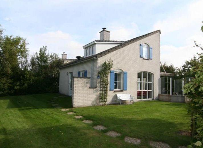 Vakantiehuis E 724 in De Cocksdorp, Texel, biedt een serene tuinomgeving met een charmante buitenkant en uitnodigende ramen.