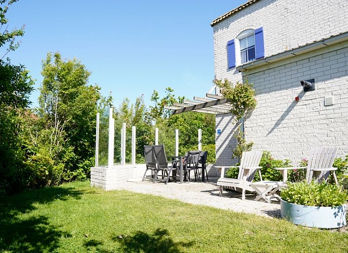 Vakantiehuis E 724 in De Cocksdorp, Texel, biedt een serene tuinomgeving met een charmante buitenkant en uitnodigende ramen.