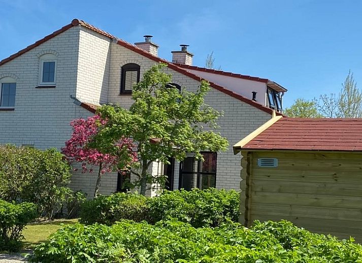 Ferienhaus D 657 in De Cocksdorp, Texel, umgeben von ueppiger Natur und bluehenden Straeuchern, ideal fuer einen erholsamen Aufenthalt auf den Watteninseln.