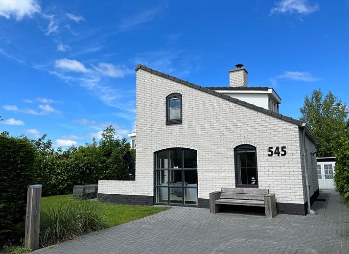 Vakantiehuis E 545 in De Cocksdorp, Texel, biedt een charmante buitenkant met een uitnodigend terras en groene omgeving op de Waddeneilanden.