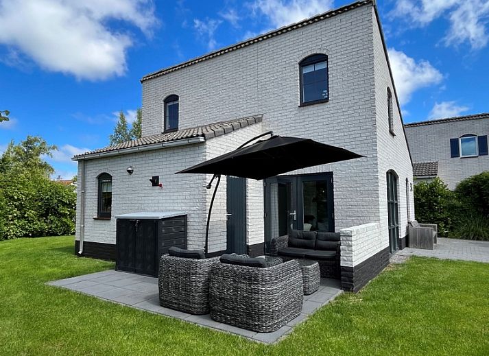 Vakantiehuis E 545 in De Cocksdorp, Texel, biedt een charmante buitenkant met een uitnodigend terras en groene omgeving op de Waddeneilanden.