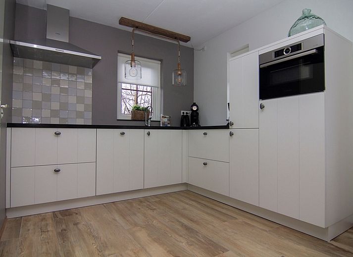 Vakantiehuis E 545 in De Cocksdorp, Texel, met charmante witte gevel en groene omgeving, ideaal voor een ontspannen verblijf op de Waddeneilanden.