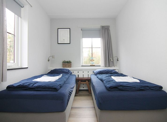 Vakantiehuis E 545 in De Cocksdorp, Texel, met charmante witte gevel en groene omgeving, ideaal voor een ontspannen verblijf op de Waddeneilanden.