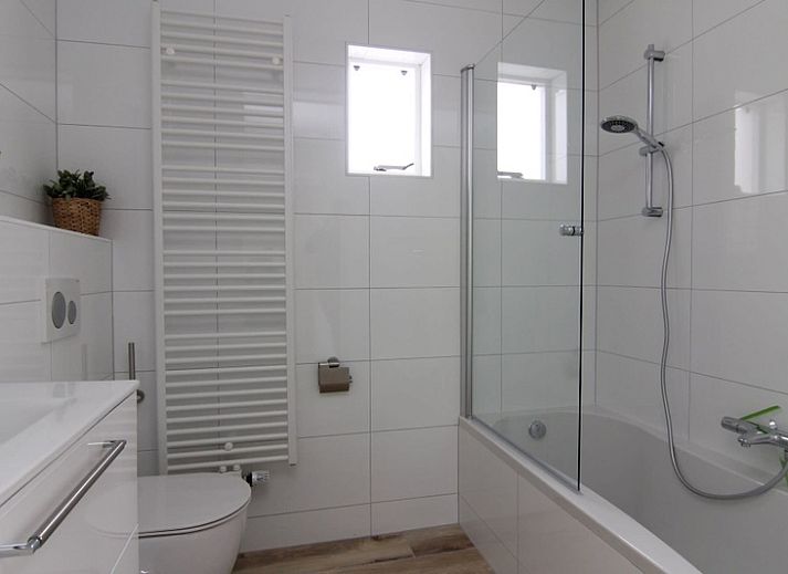 Vakantiehuis E 545 in De Cocksdorp, Texel, met charmante witte gevel en groene omgeving, ideaal voor een ontspannen verblijf op de Waddeneilanden.