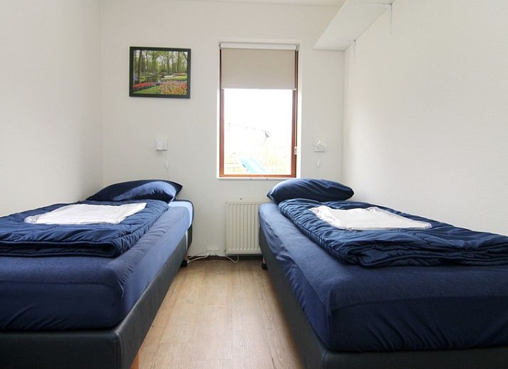 Vakantiehuis F 654 in De Cocksdorp, Texel, omgeven door groene tuin en blauwe lucht, ideaal voor een ontspannen verblijf op de Waddeneilanden.